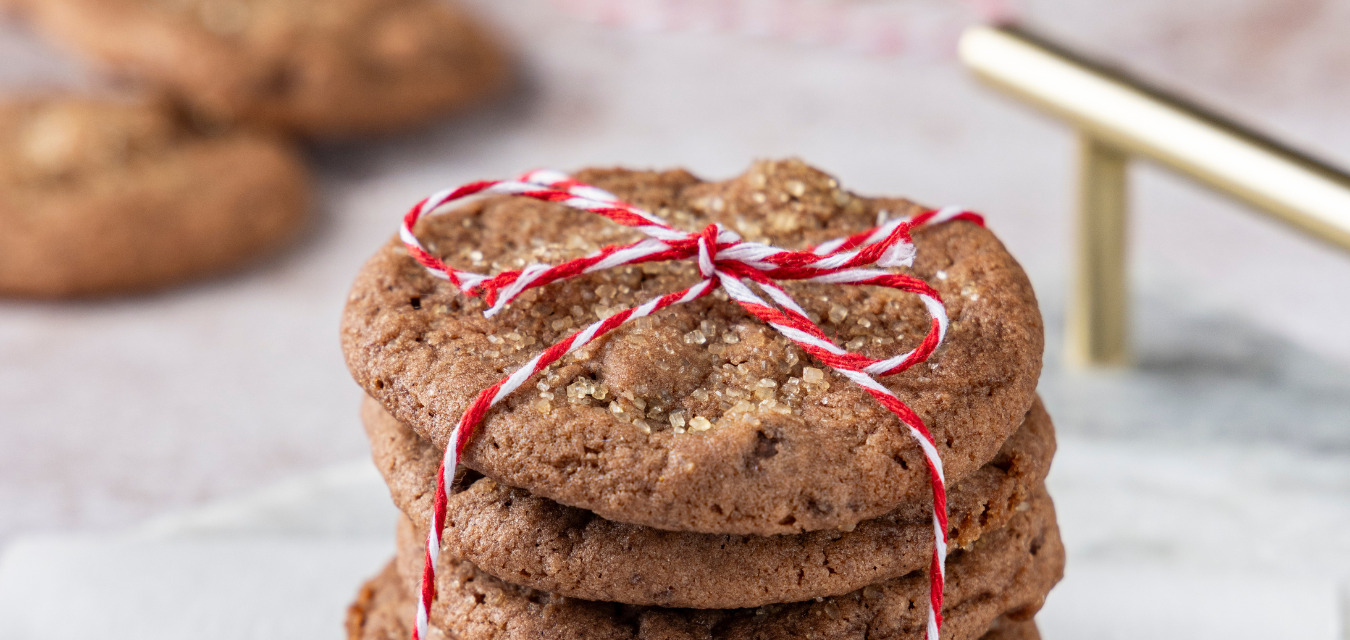chocolate gingerbread cookies: an image of a stack of 3 round gingerbread cookies topped with coarse sugar and a red and white striped bow around them