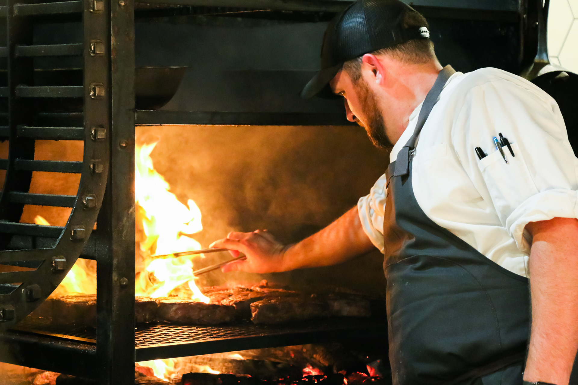 Man grilling meat on an open flame at The Appalachian in Sevierville, Tennessee