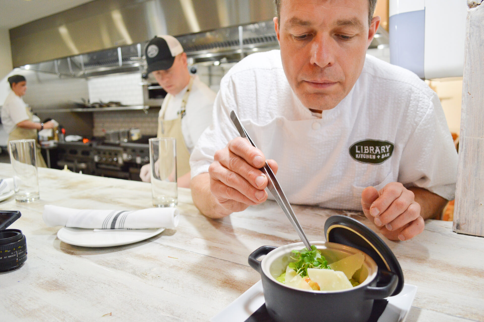 A chef plates a dish at The Library Kitchen + Bar