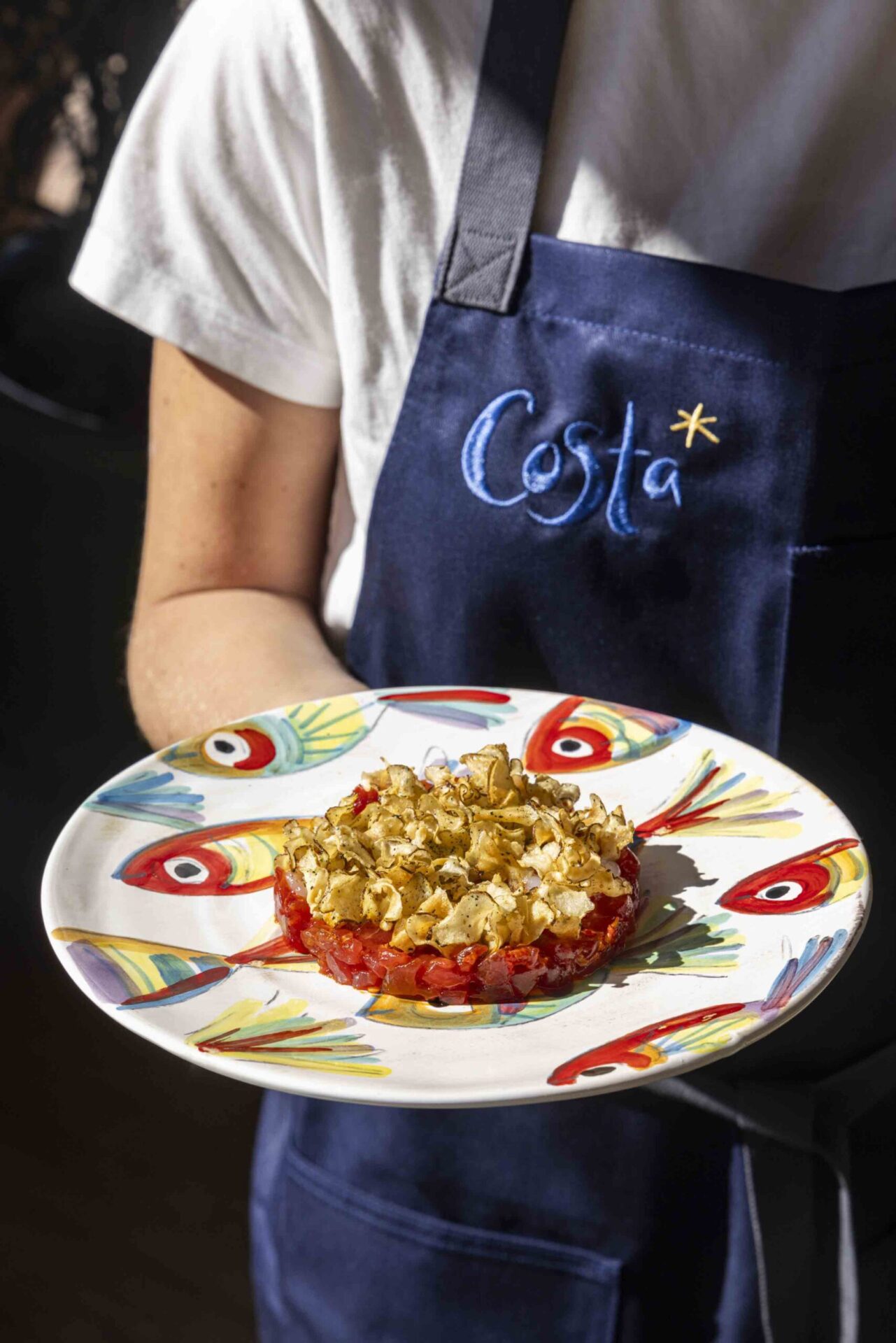 Tuna at Costa on a plate held by someone in an apron