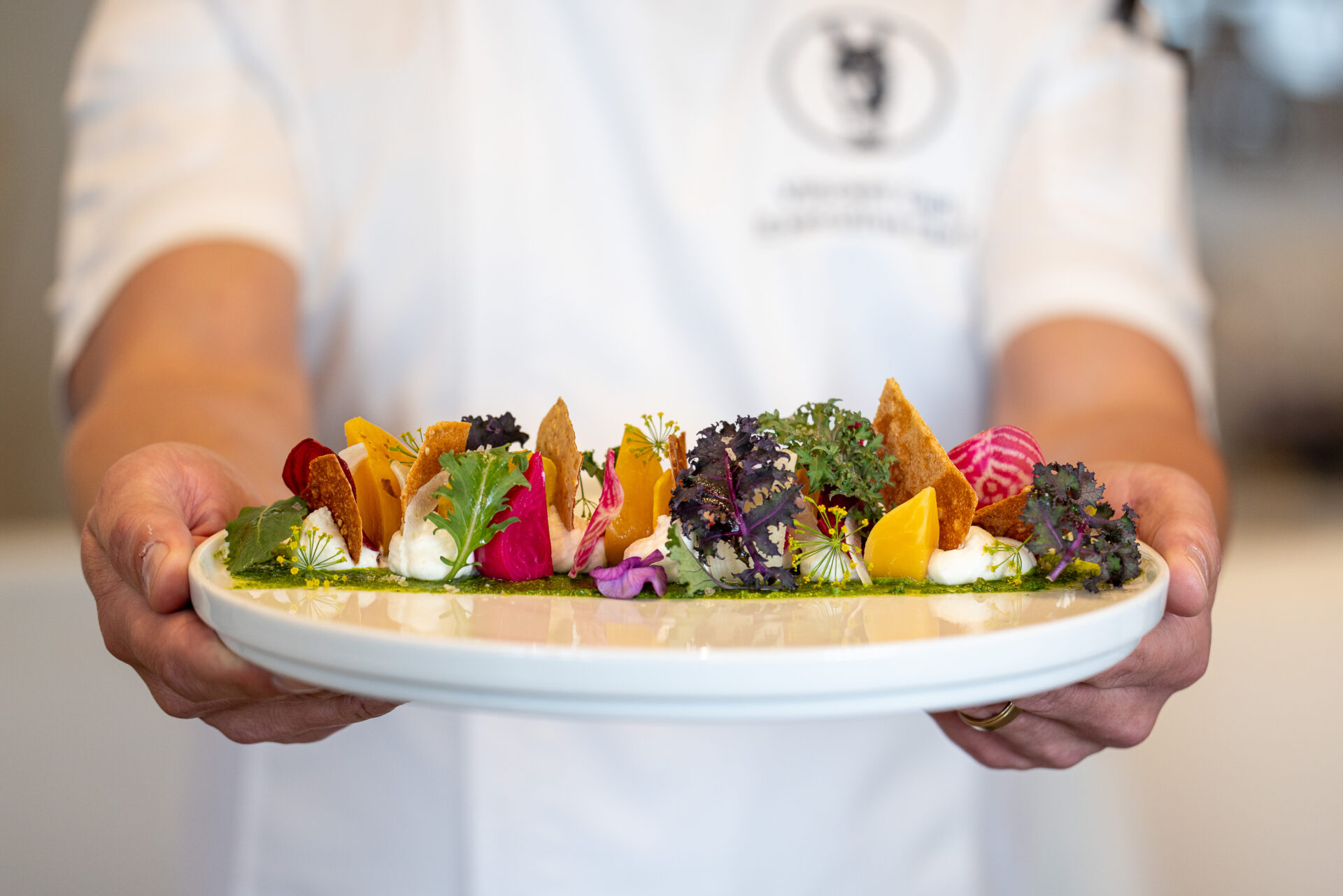 Chef holding a plate of food from Stirrups Restaurant at The Equestrian Hotel in Ocala, Florida.