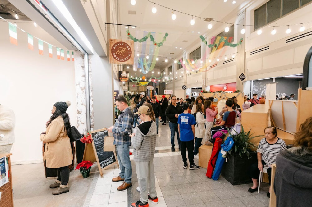 A crowd of people wait in line in a market in Norfolk