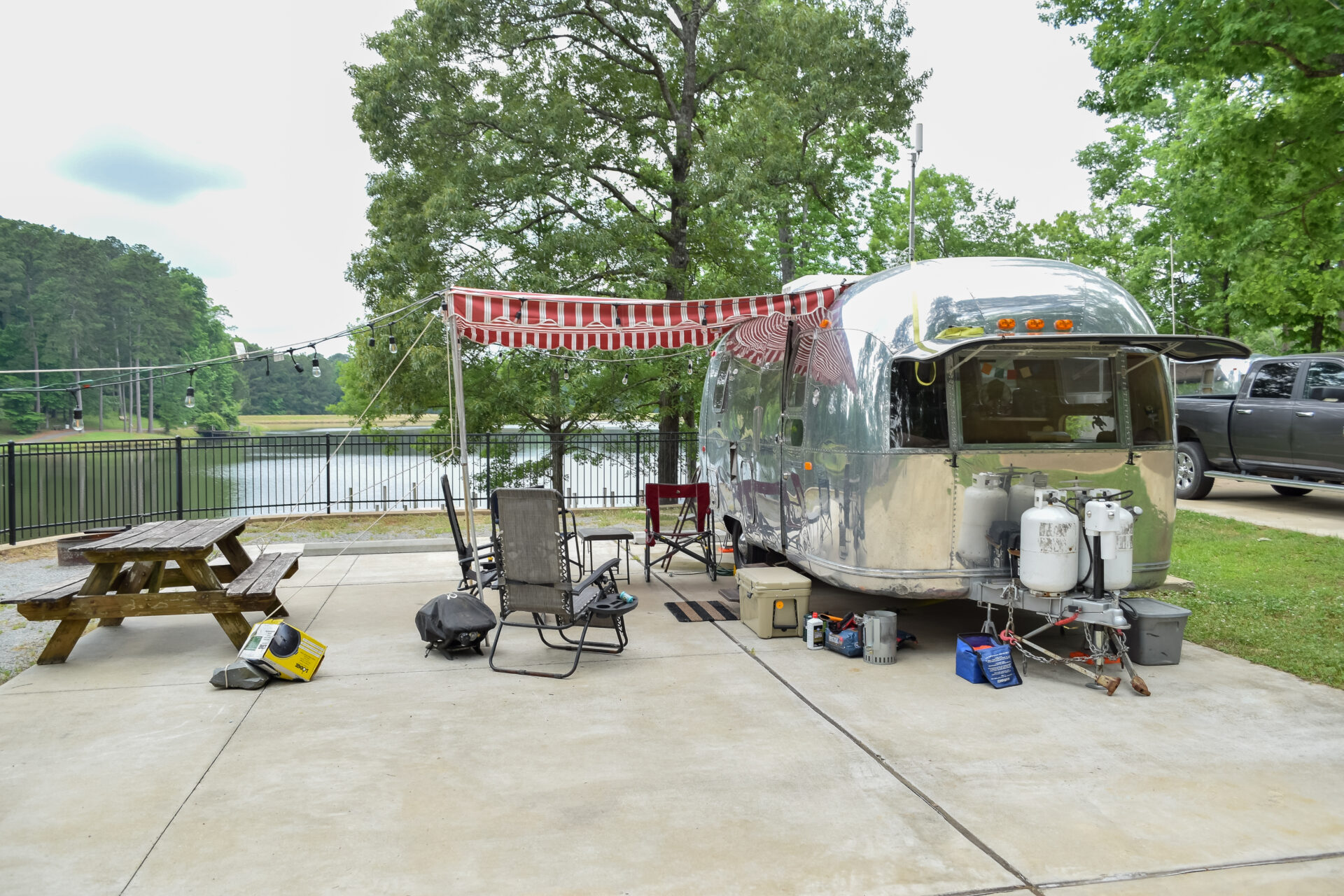 An RV site with an overhang covering three lawn chairs, facing Hoogland Lake at Lincoln Parish Park in Ruston, Louisiana. 