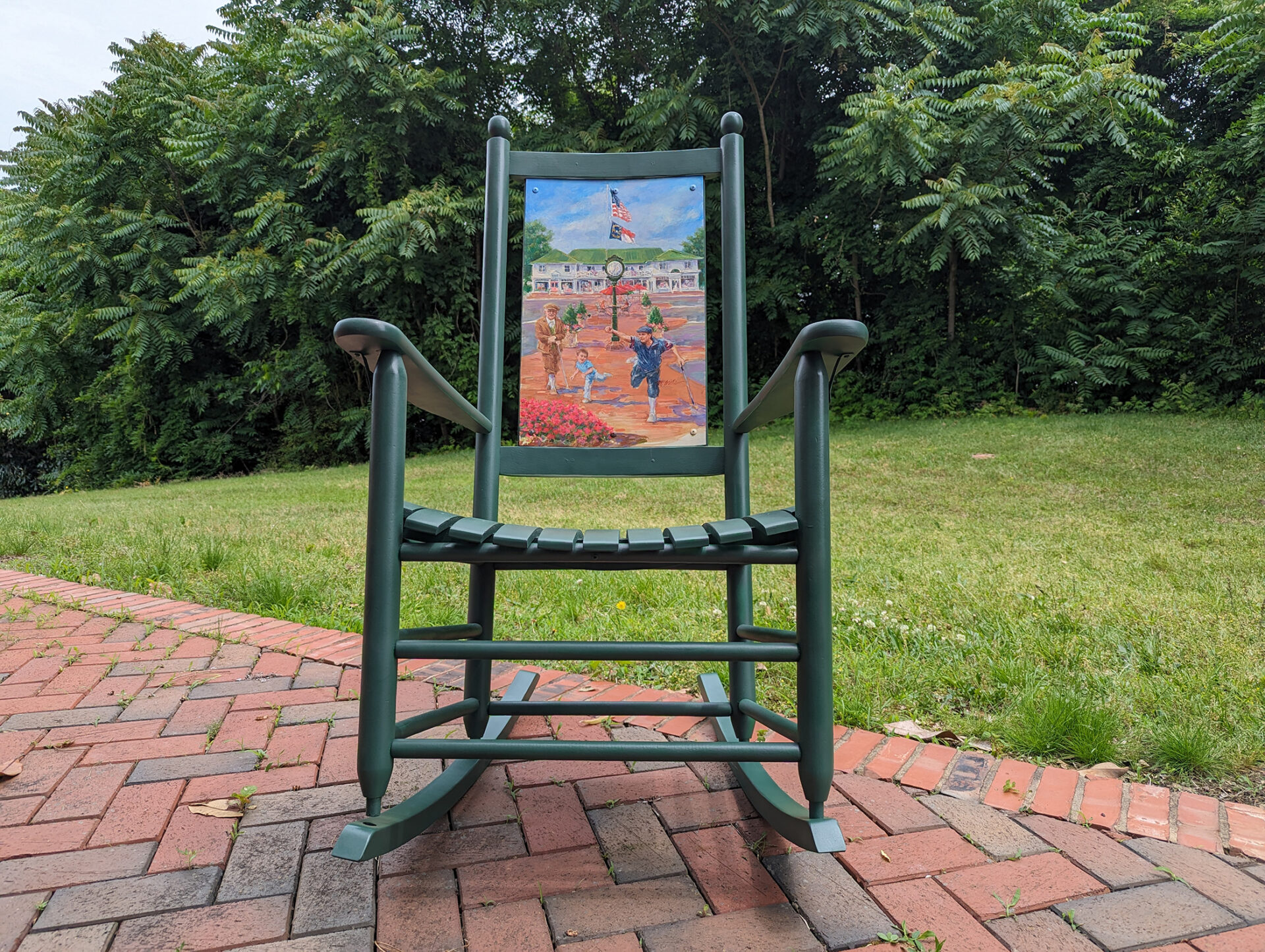 A Rock the Village rocking chair that is painted with designs of Pinehurst, NC.