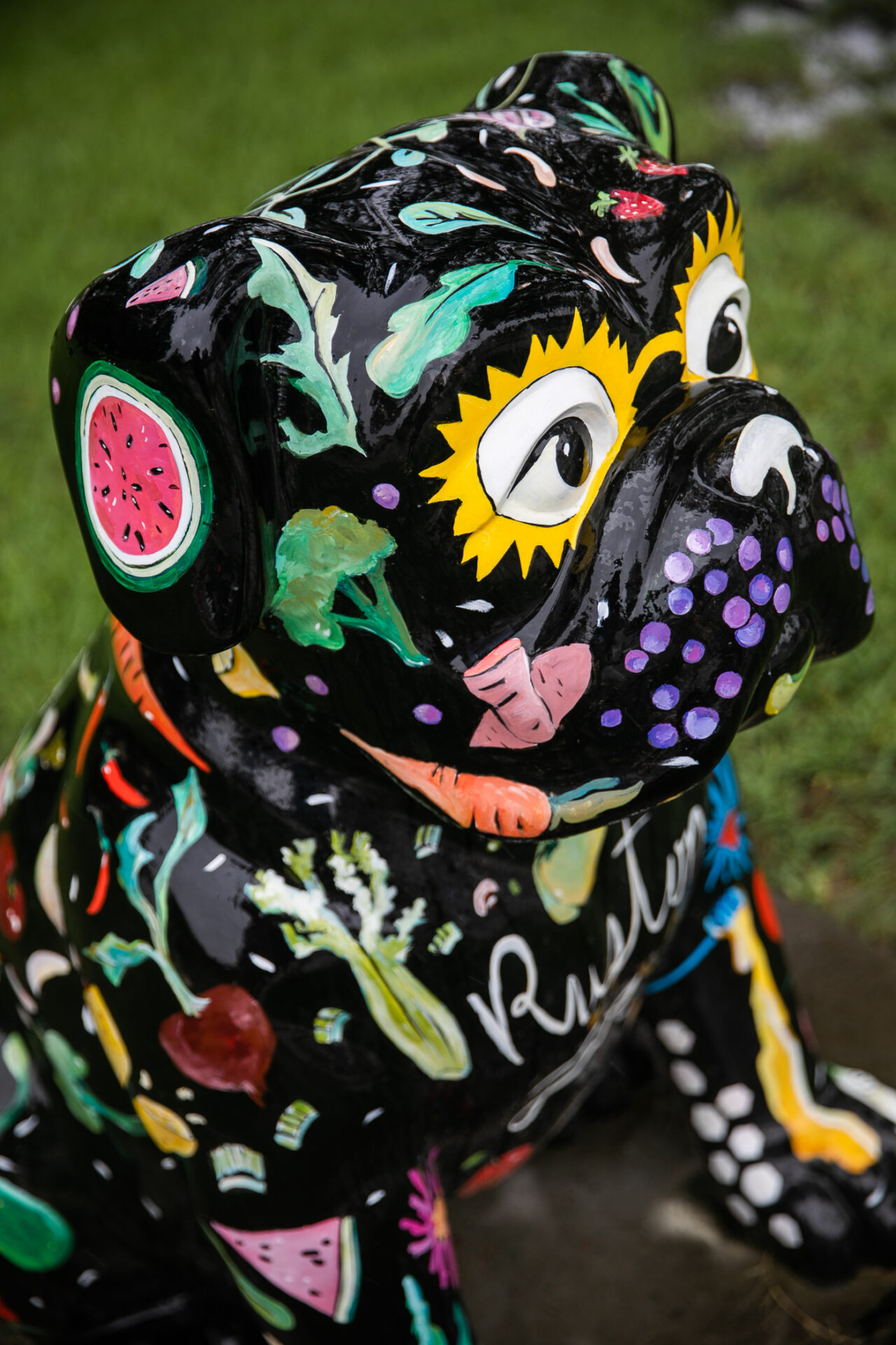 The Farmers Market bulldog sculpture in Ruston features a black colored bulldog with images of colorful vegetables and fruits throughout its body.