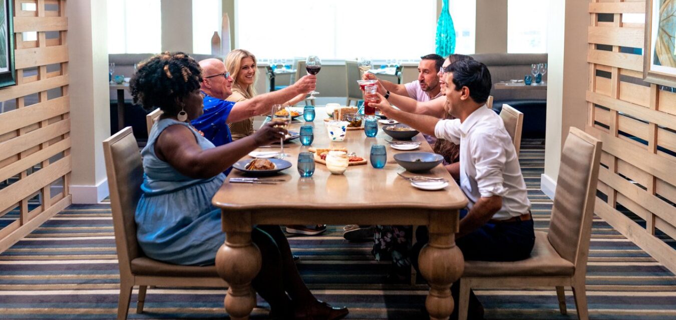 A group of people dining and raising a glass to toast at Verandah at Omni Amelia Island Resort