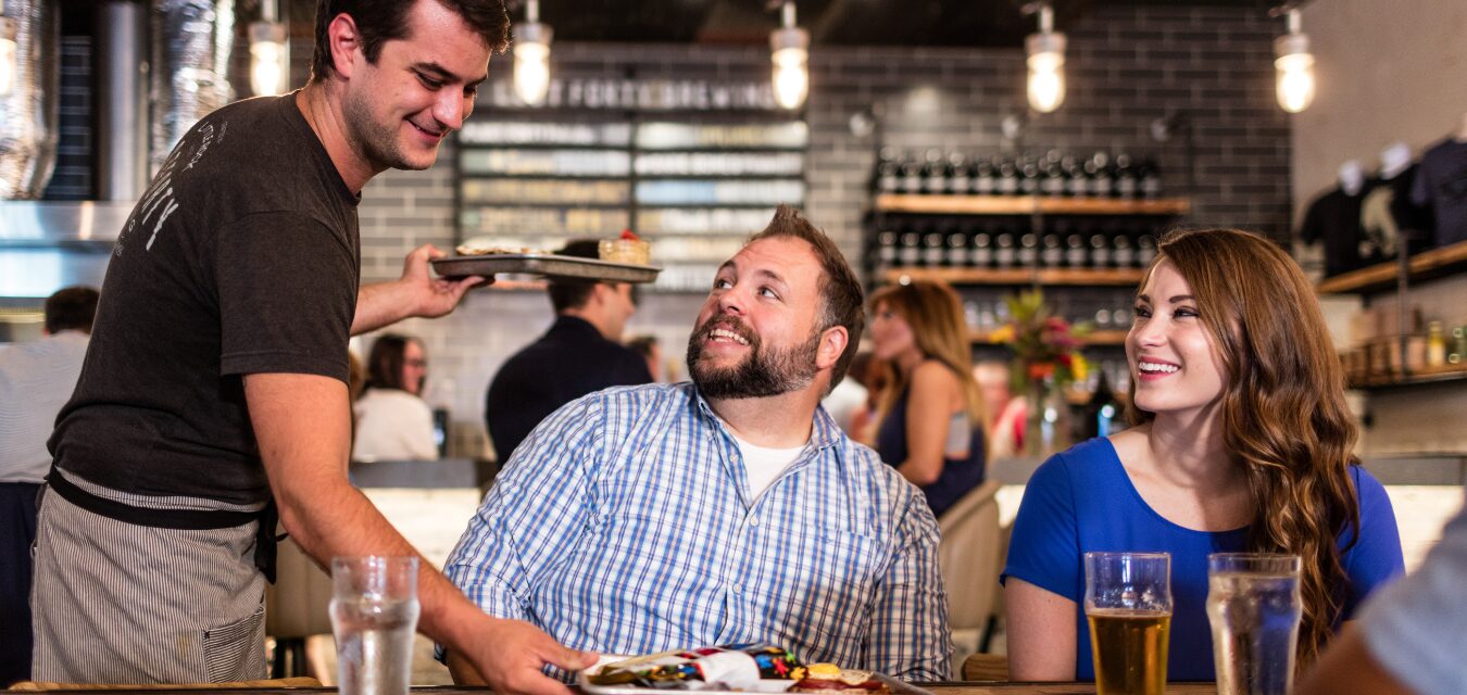 A man and women being served beer and food at Lost Forty Brewing in Little Rock, Arkansas.