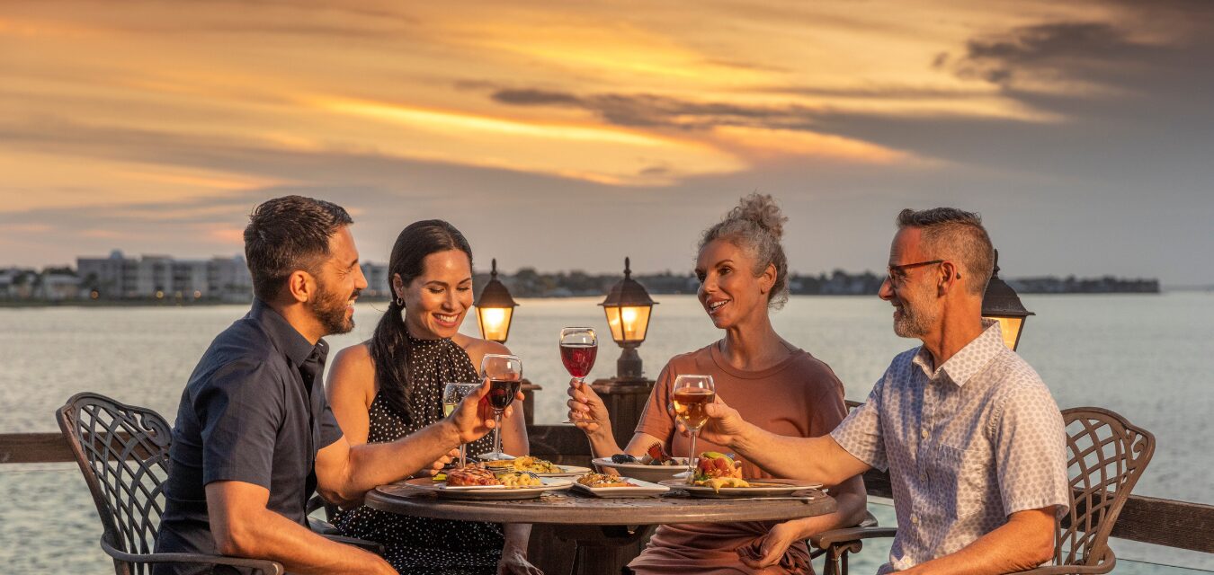 A group of people enjoying a meal with a waterfront view at The Captain's Table on Charlotte Harbor in Punta Gorda, Florida