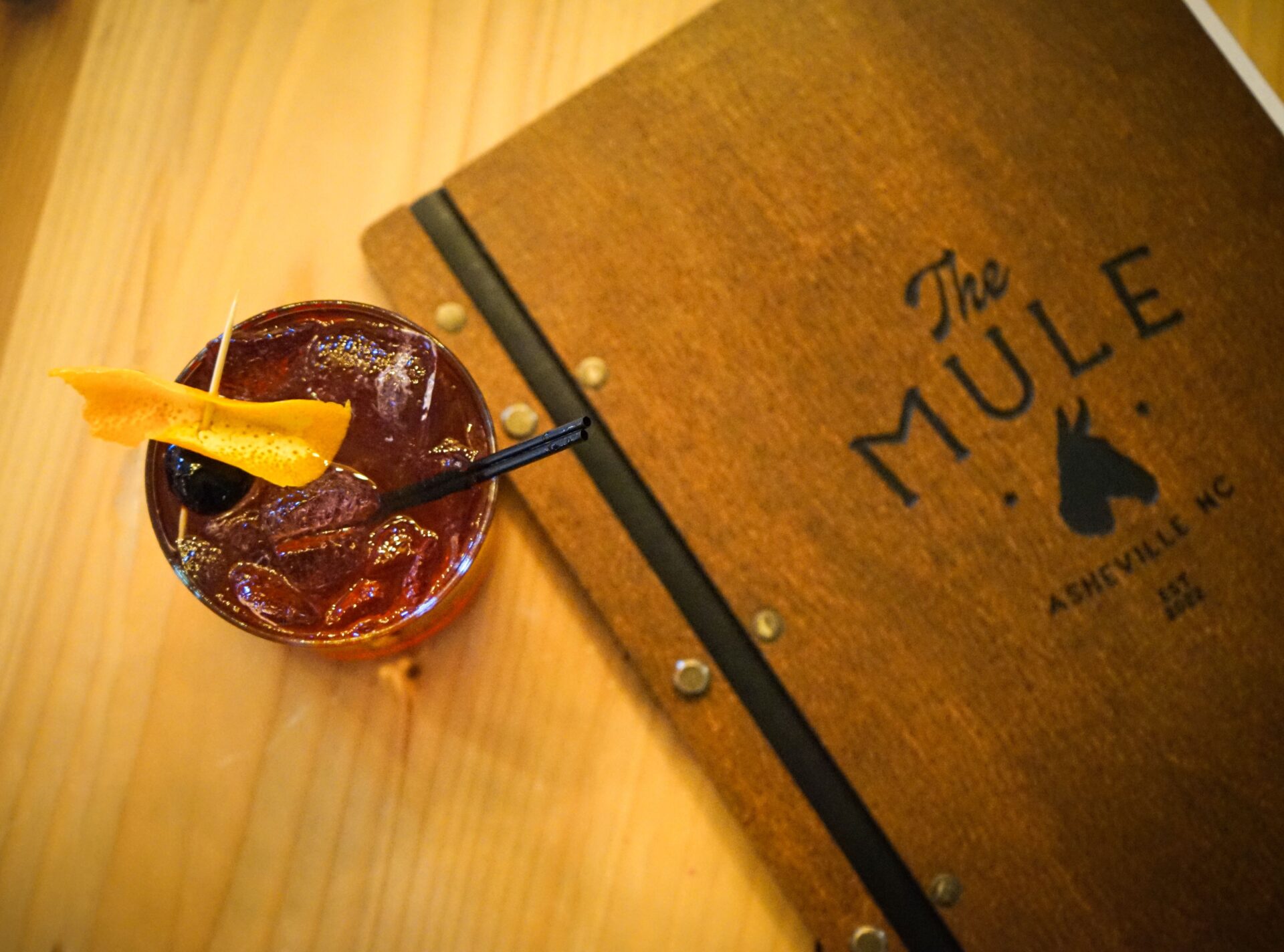 A red cocktail with an orange twist from The Mule in Asheville, a featured dry bar