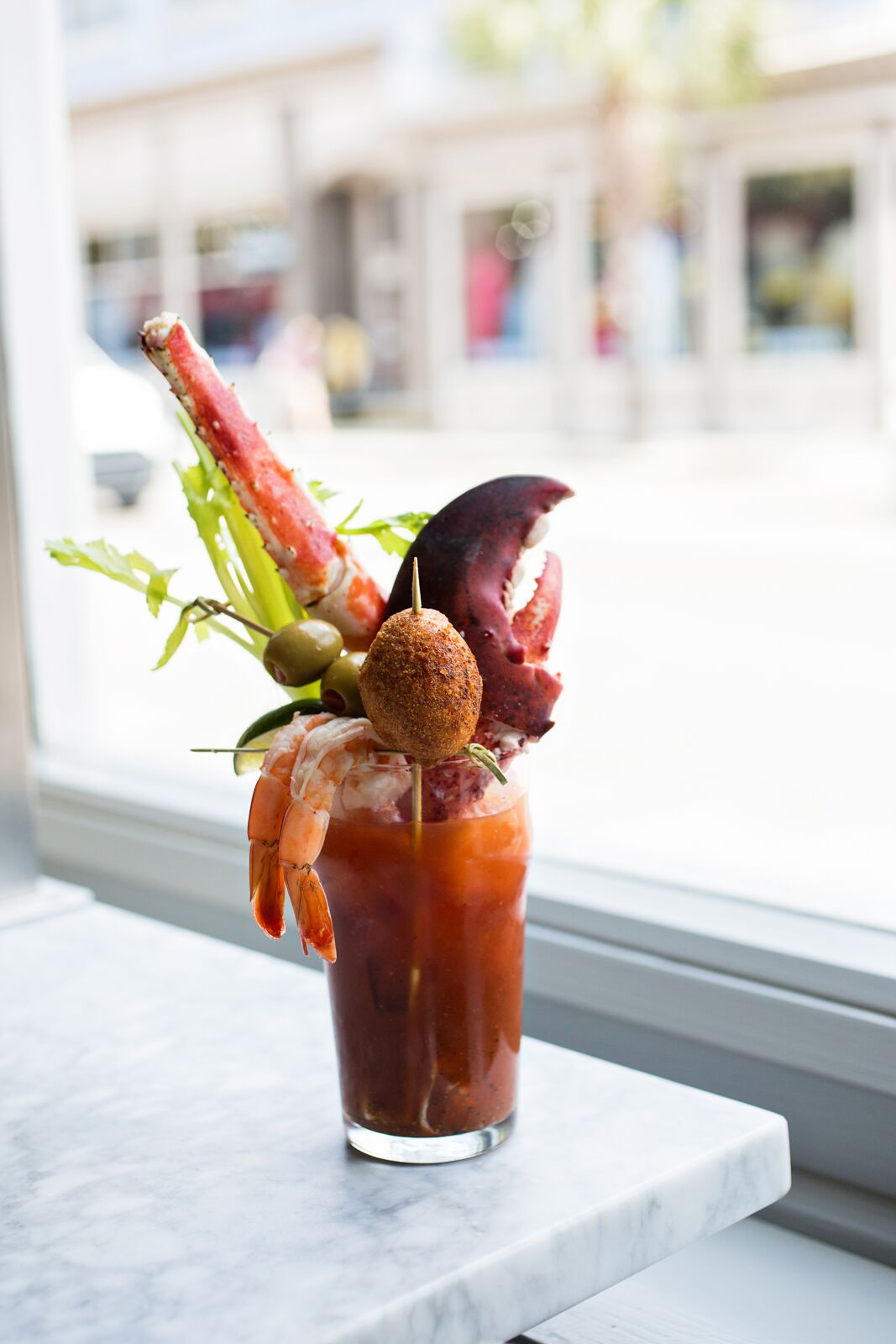 Bloody Mary adorned with lobster claws, crab legs, pickled shrimp, celery, olives, and house made hushpuppies at The Darling in Charleston, South Carolina