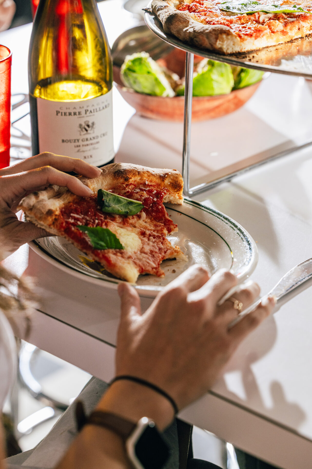 A slice of pizza next to a bottle of wine