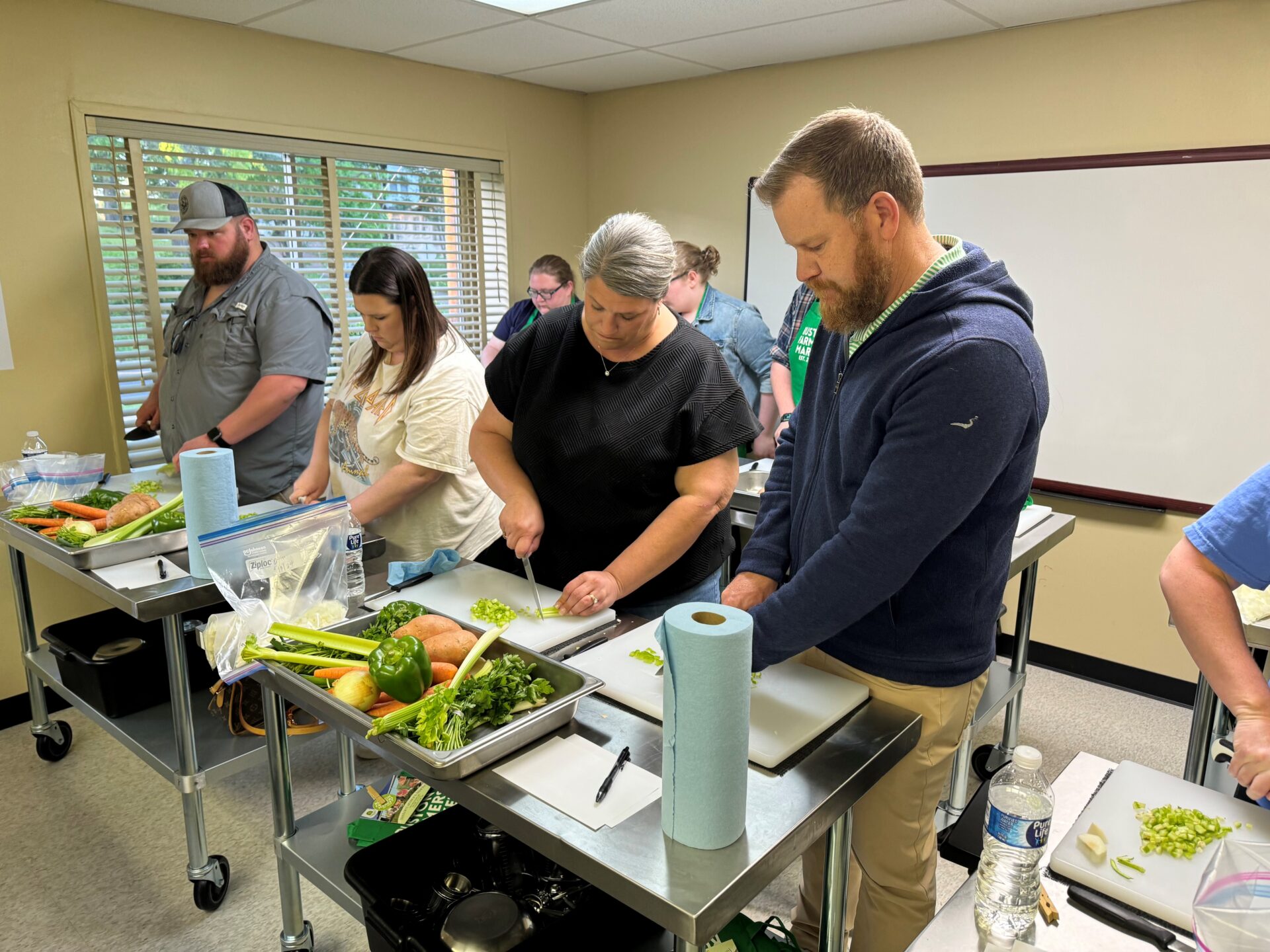 Seven adults chop fresh vegetables at the Drew Jones Teaching Kitchen in Ruston, Louisiana.