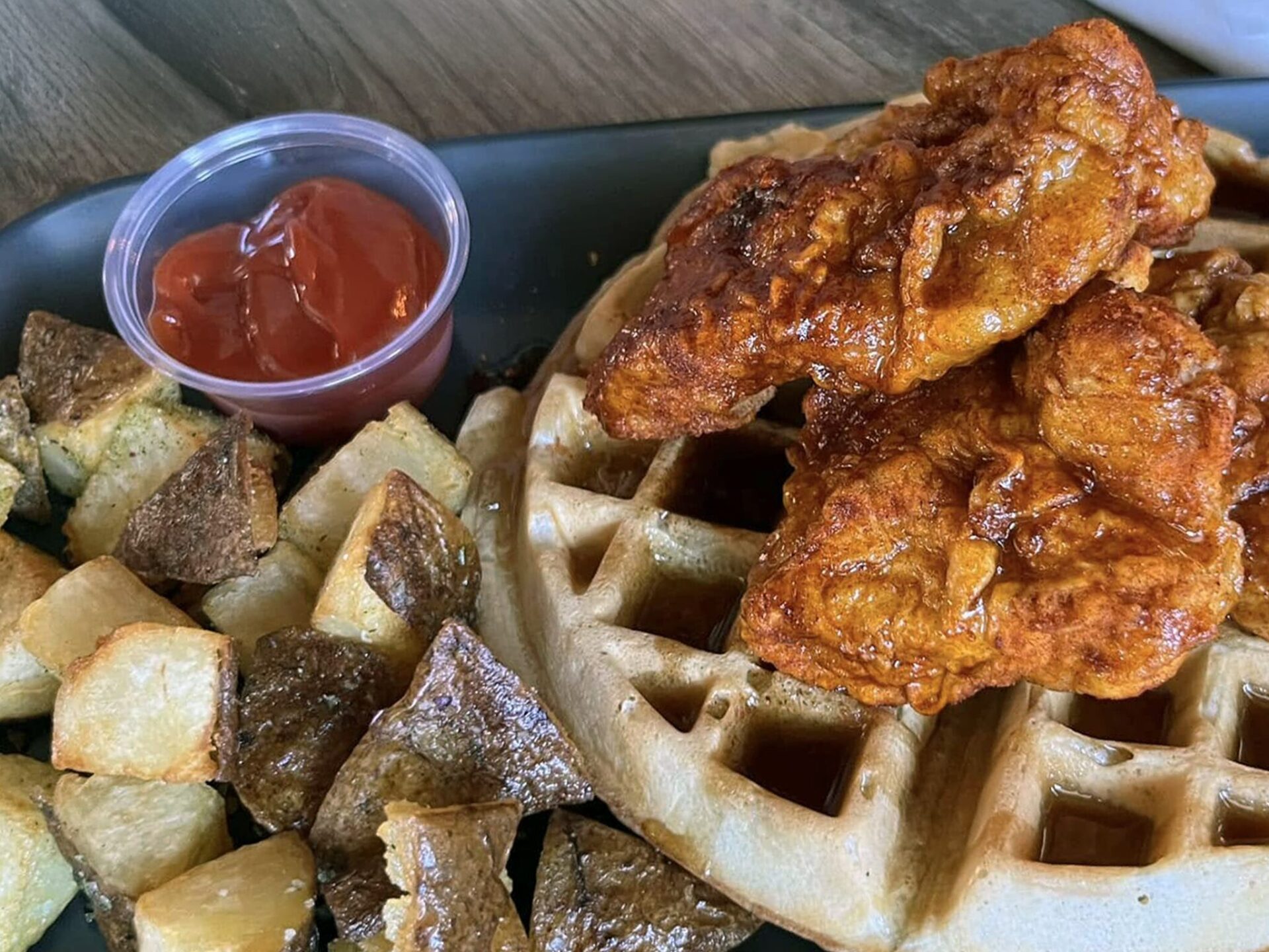 A plate of chicken and waffles with homefries glistens at the Salted Goat, a farmer-driven gastropub in West Volusia, Florida.