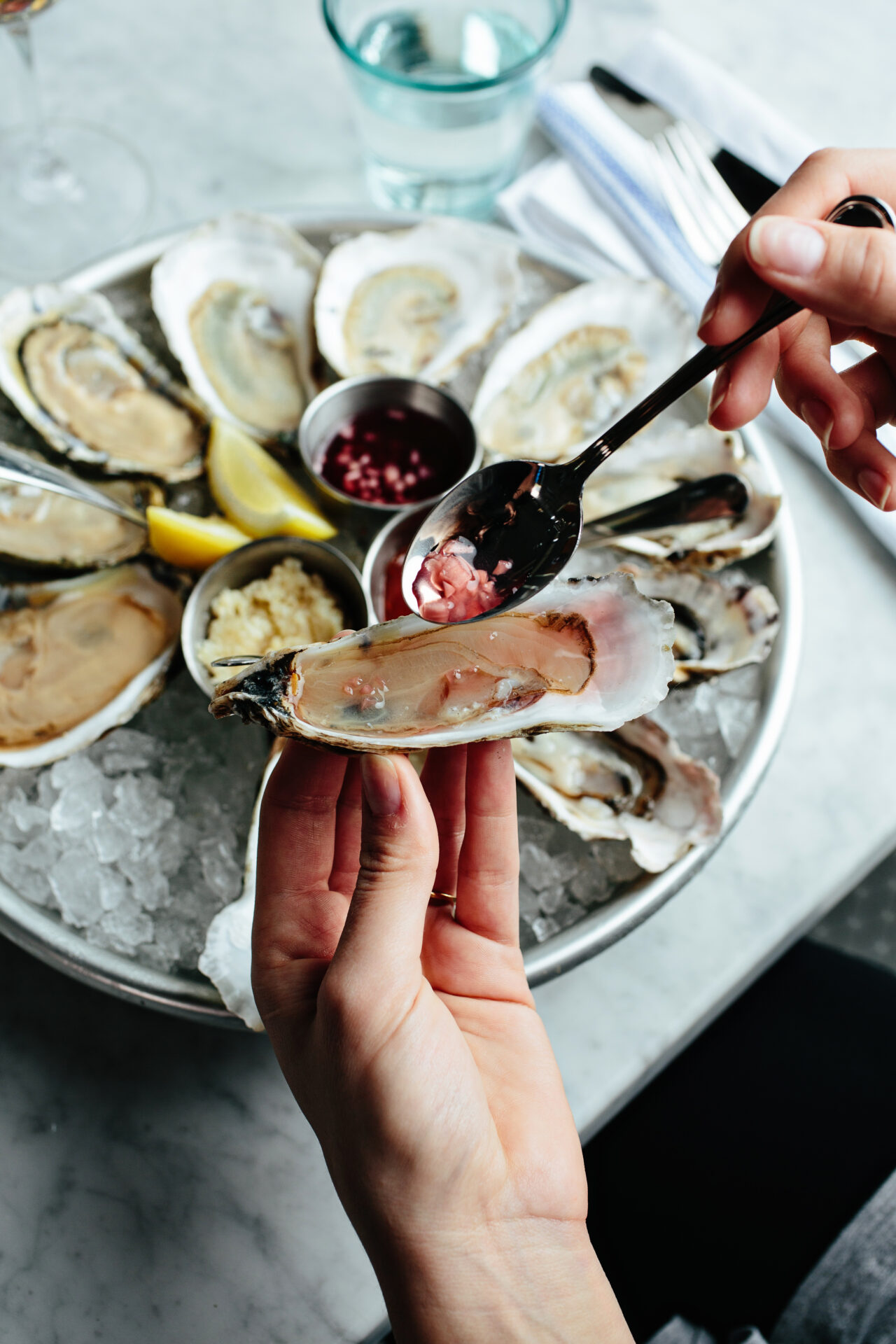 An oyster is seasoned with condiments over a plate of fresh oysters in a bed of ice at the Darling Oyster Bar in Charleston, South Carolina.