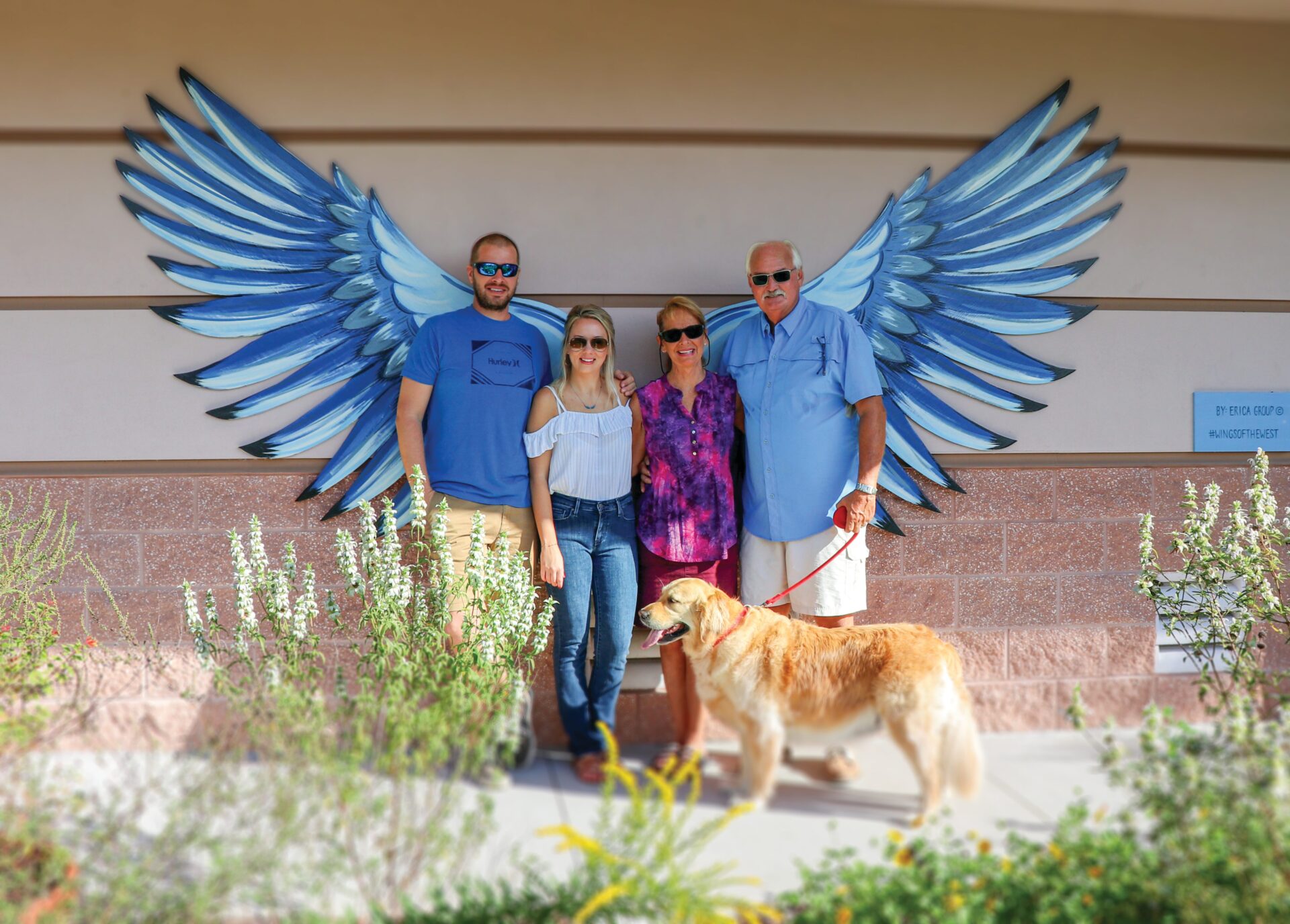 Four poeple and a golden retriever pose in front of one of the Wings on The Wings of the West Mural Trail in West Volusia, Florida