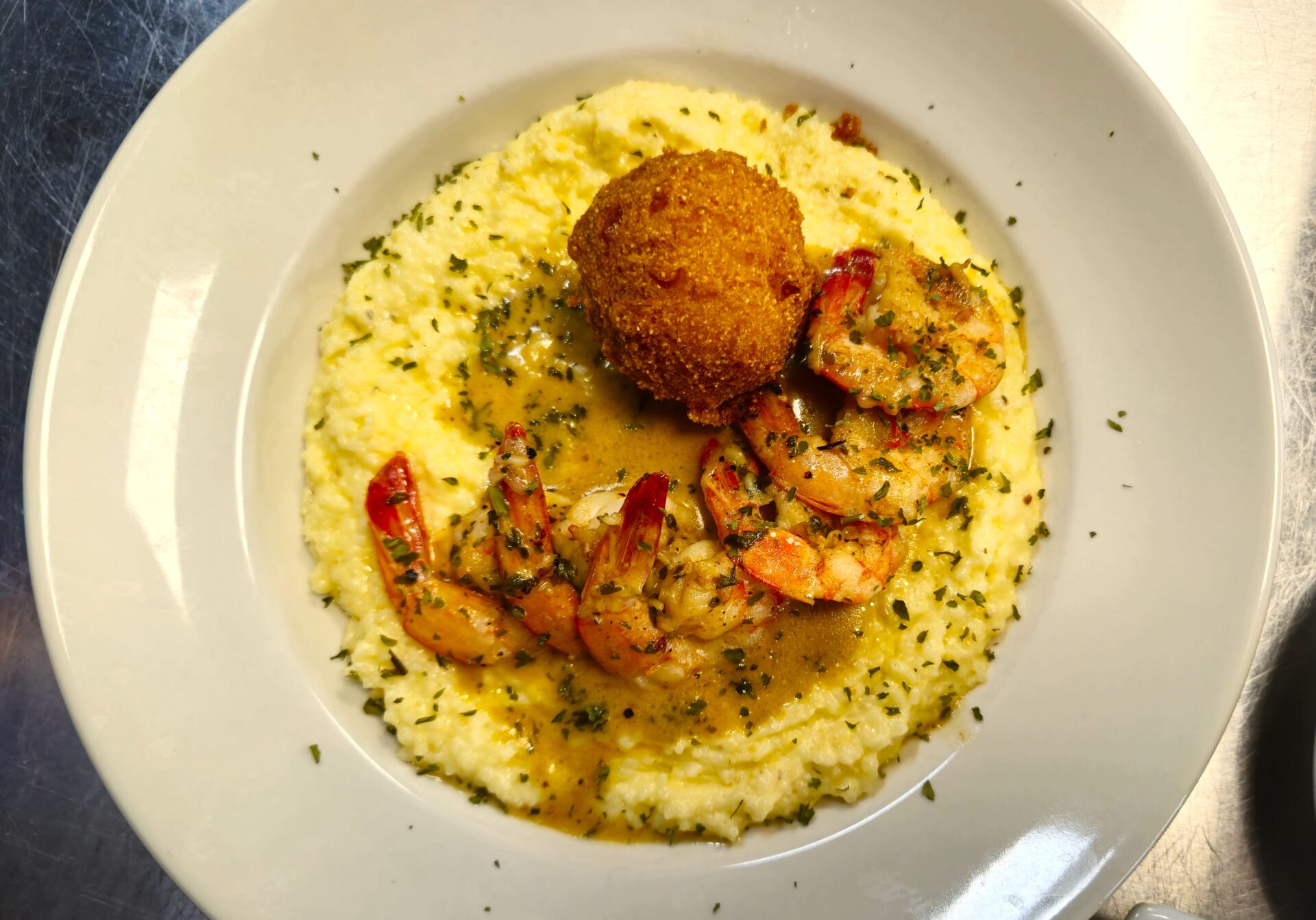 Griffin's Restaurant showcases a plate of Cajun shrimp, grits, gravy, and a golden-brown hushpuppy in Cajun Bayou, Louisiana.