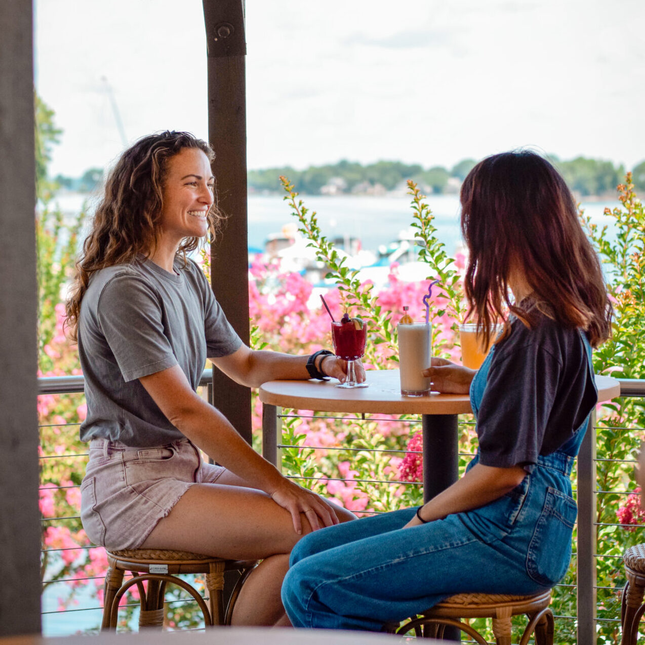 Two women enjoy drinks on Hello Sailor's patio overlooking the lake in Lake Norman, North Carolina.