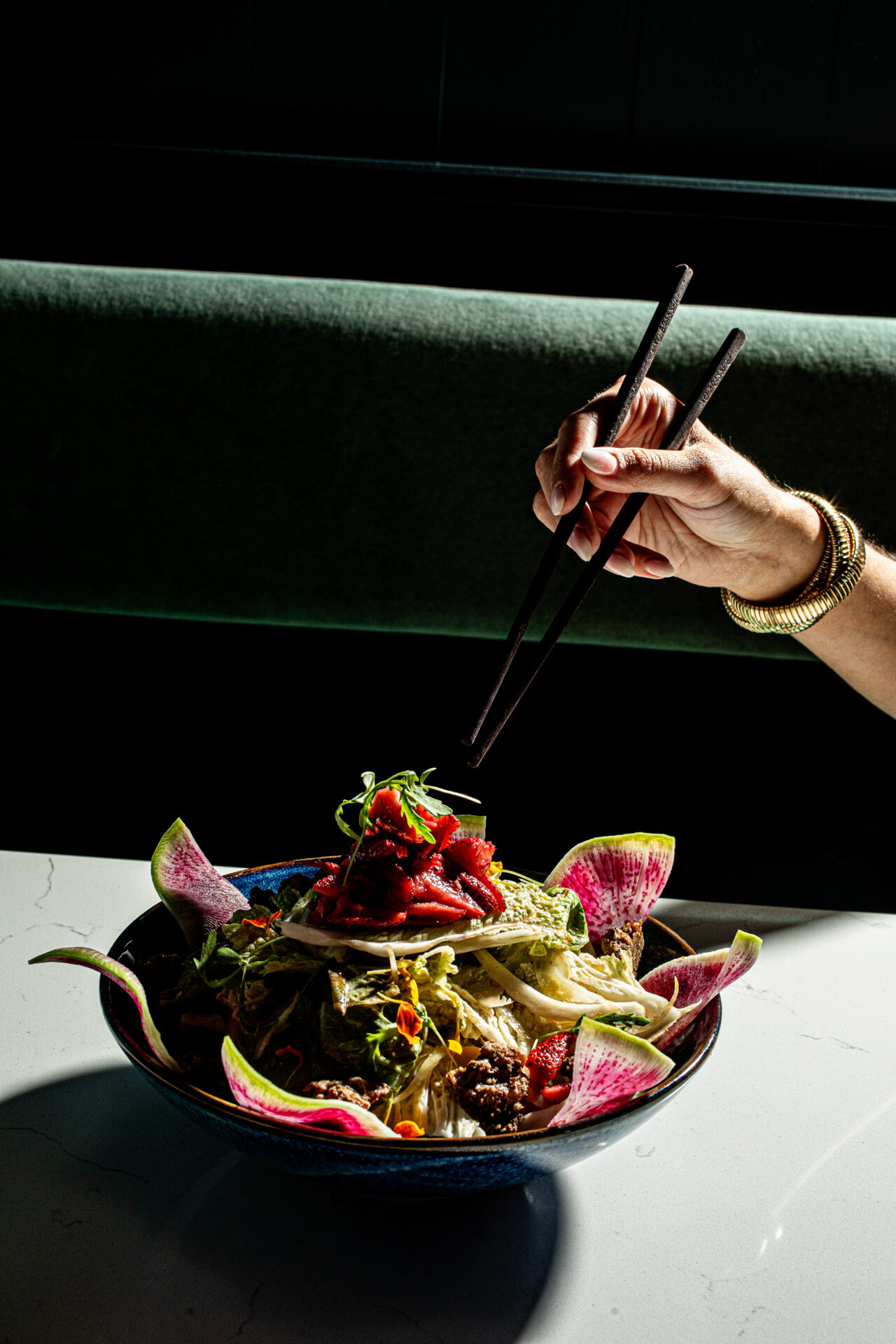 Hands holding chopsticks digging into a bowl at Xo Brasserie